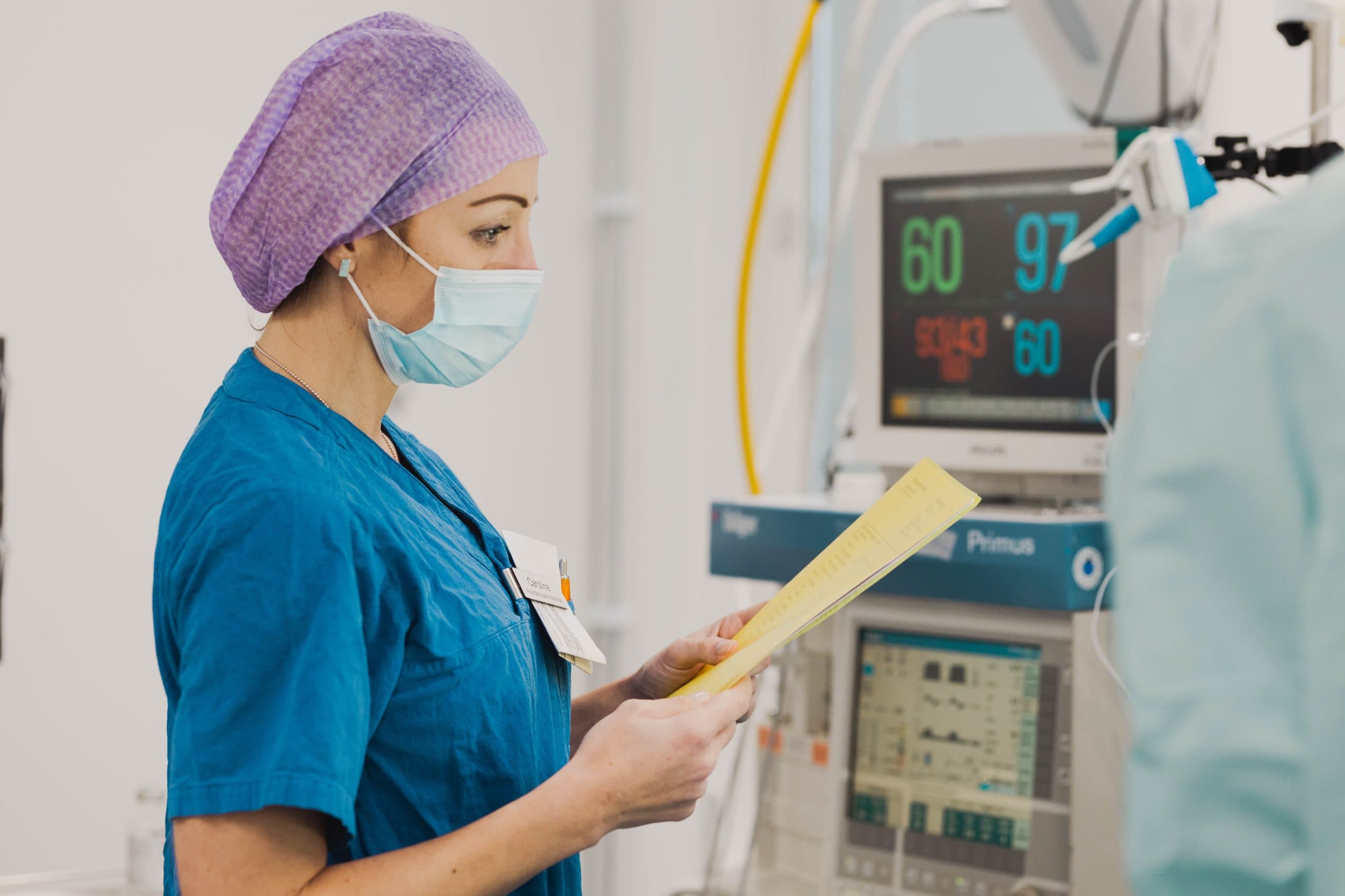 Sjuksköterska övervakar vitala tecken på en monitor under operation, med fokus på patientens säkerhet.